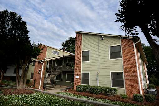 A two-story apartment building with a green siding and a brick base.