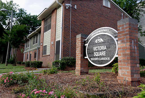 A sign for Victoria Square is in front of a brick building.