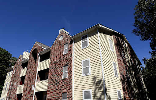 A tall apartment building with a red brick base and beige siding.