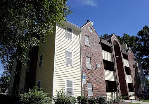 A building with a yellow siding and a brick section with a white sign on it.