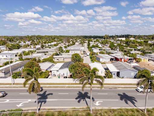 A street view of a residential area with houses and palm trees.