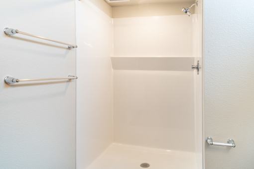 A white bathroom with a toilet and a shower.at All Saints Apartments, DENVER
