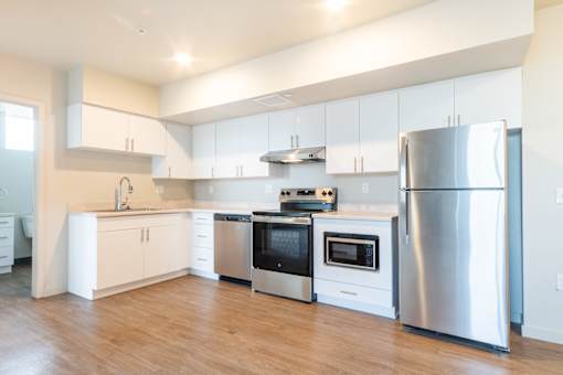 A modern kitchen with stainless steel appliances and wooden floors.  at All Saints Apartments, Colorado, 80219
