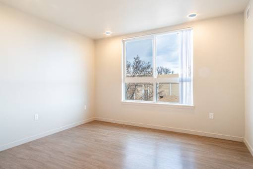 A room with a large window and wooden flooring. at All Saints Apartments, DENVER, Colorado