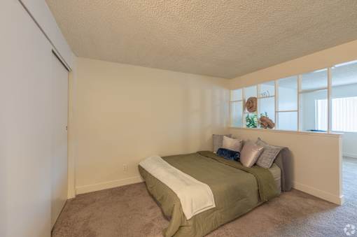 A bedroom with a bed and a carpeted floor.