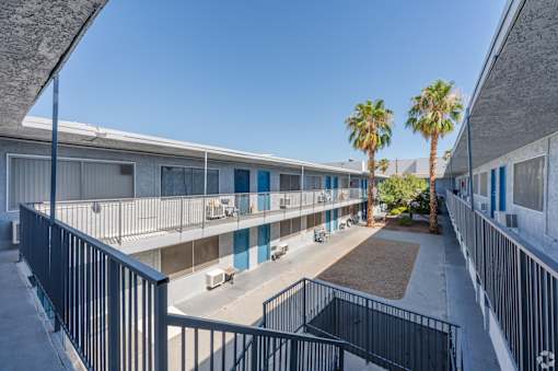 Balcony view of a courtyard with palm trees between apartment buildings.