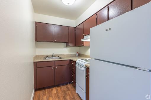 A kitchen with brown cabinets and a white fridge.