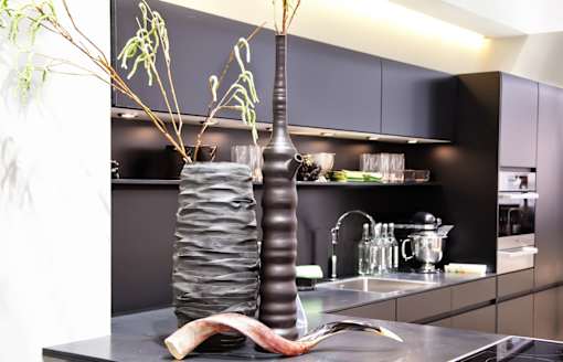 A tall vase with a plant in it is on a counter.