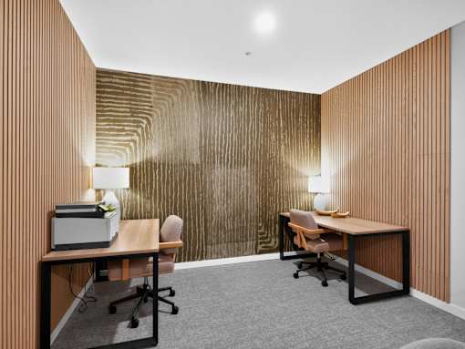 Two desks with chairs and lamps in a room with wooden paneling.