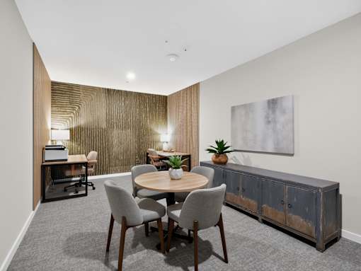 A room with a wooden table surrounded by grey chairs and a wooden cabinet.