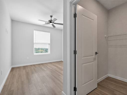 A room with a ceiling fan and a door leading to another room.