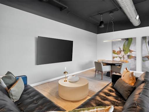 A living room with a black couch and a flat screen TV mounted on the wall.
