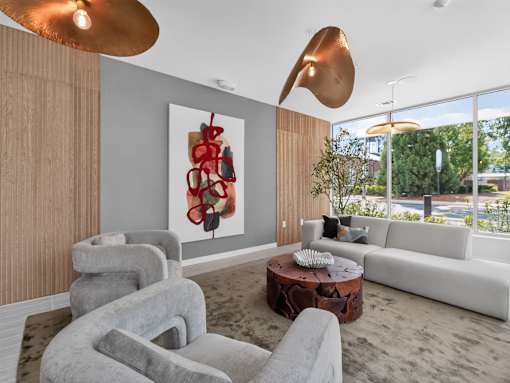 A modern living room with a grey sofa, a round coffee table, and a large abstract painting on the wall.