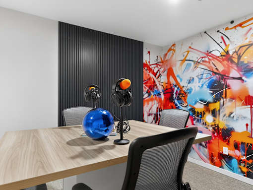 A room with a wooden table and a wall with a colorful painting.