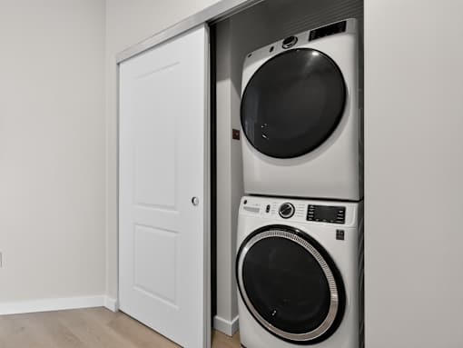 A white door is open to a small laundry room with a washer and dryer.