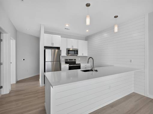 A modern kitchen with a white countertop and stainless steel appliances.