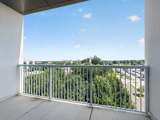 A balcony with a metal railing overlooks a city street.