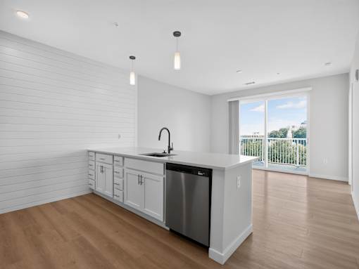 A kitchen with white cabinets and a wooden floor.