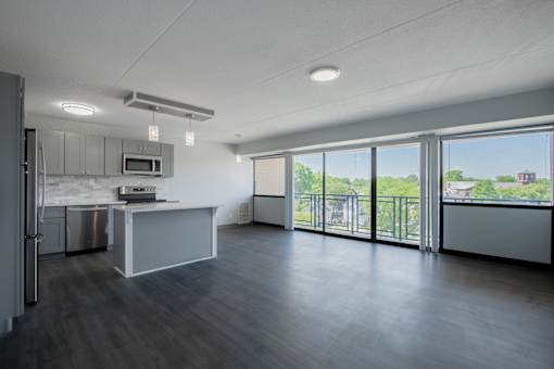 an empty living room with a kitchen and a balcony