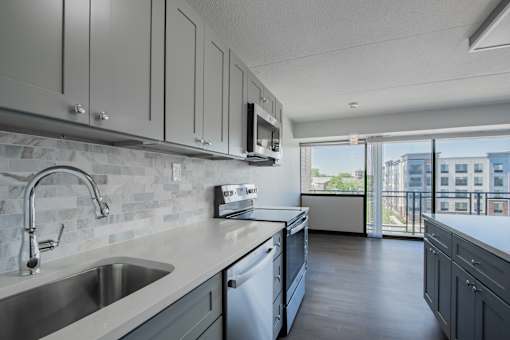 an open kitchen with white cabinets and a sink and a window