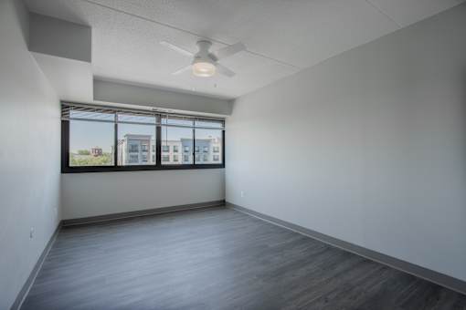 an empty living room with a window and a ceiling fan