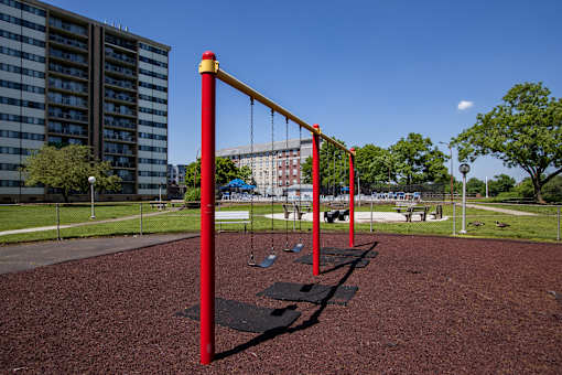 a swing set in a park with a building in the background