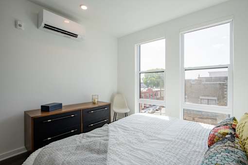 Primary bedroom with city views and minimalist design in The Rail’s luxury apartments in Bound Brook, offering comfort and tranquility.