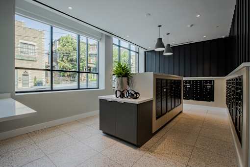 A modern mail room lobby with a reception desk and a view of the outside at The Rail at Bound Brook, NJ.