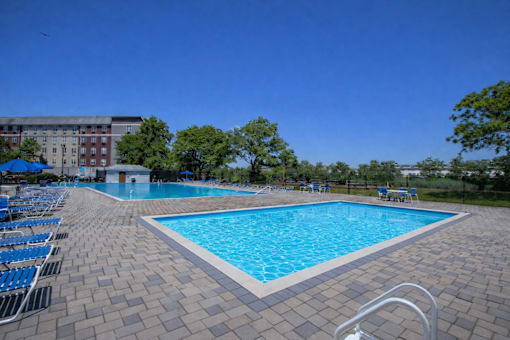 A large swimming pool surrounded by blue lounge chairs.