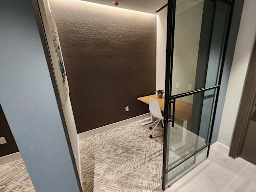 A modern work space with a glass door and a wooden desk at The Rail at Bound Brook, NJ.