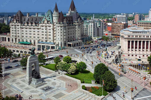 A large building with a green roof and a monument in front of it.