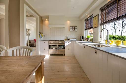 A modern kitchen with a wooden table and white cabinets.
