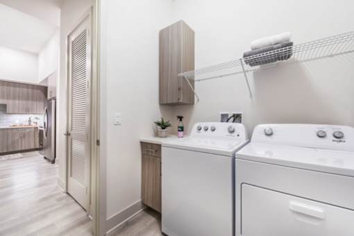 a utility room with a washer and dryer and a kitchen in the background
