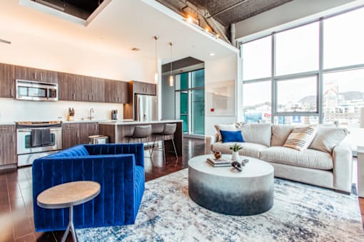 a living room with a couch coffee table and a kitchen with a breakfast bar