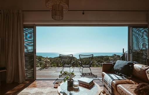 A living room with a view of the ocean through the sliding glass doors.