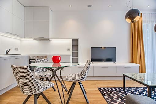 A modern kitchen with a glass table and chairs.
