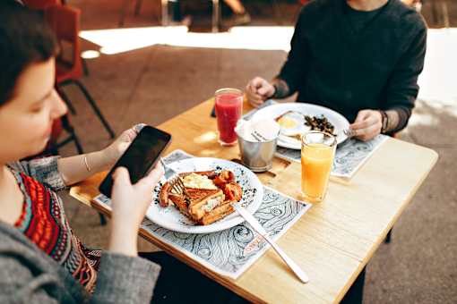 A person is sitting at a table with a plate of food and a glass of juice.