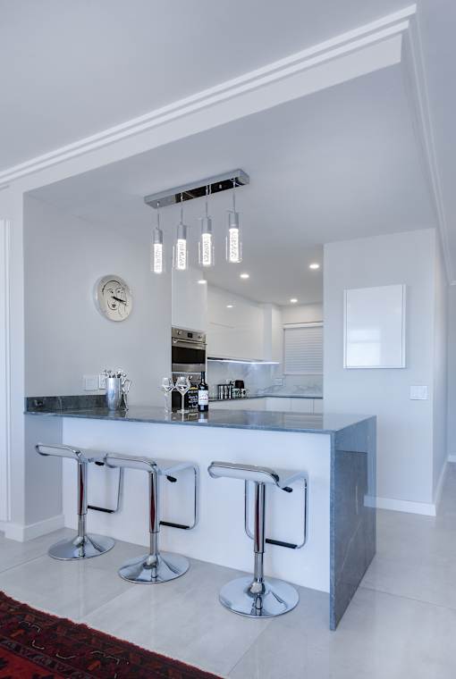 a kitchen with a long counter and three stools in front of it
