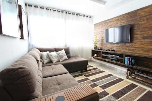 a living room with a large brown couch and a flat screen tv on the wall
