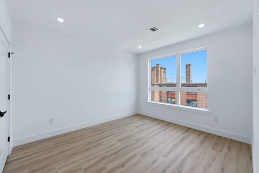 A room with a large window and wooden flooring.