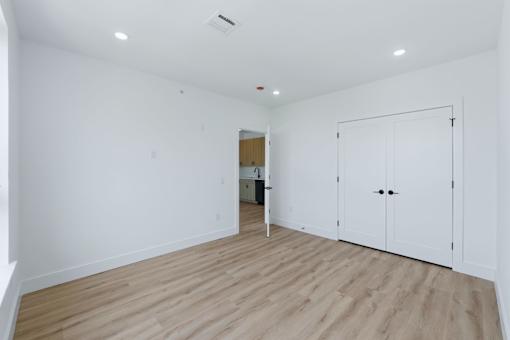 A white room with a wooden floor and a white door.