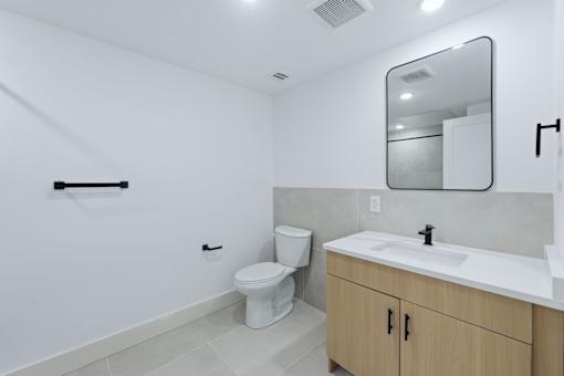 A white bathroom with a toilet, sink, and mirror.