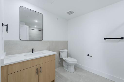 A white toilet sits in a bathroom with a sink and mirror.