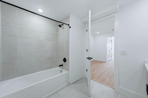 A white bathroom with a tub and a door.
