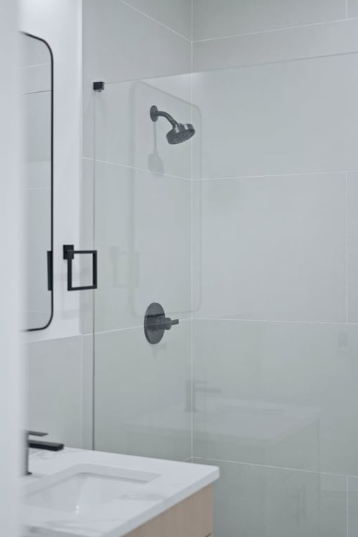A white sink in a bathroom with a glass shower door.