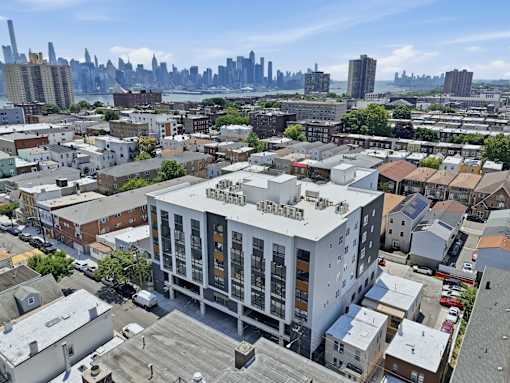 A modern building with a flat roof is surrounded by other buildings.