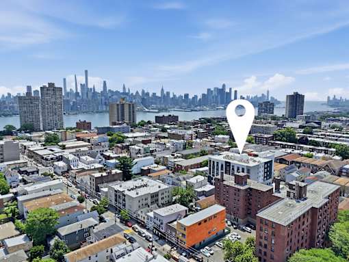 A cityscape with a white location marker in the foreground.