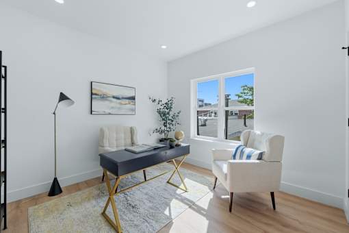 A room with a desk, chair, and a window overlooking a street.