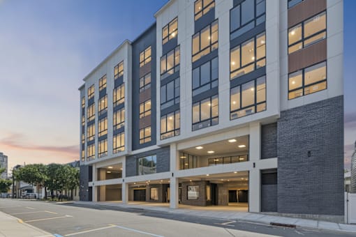 A modern building with a lot of windows and a parking lot in front.