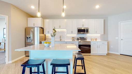 A kitchen with a white counter and blue stools.